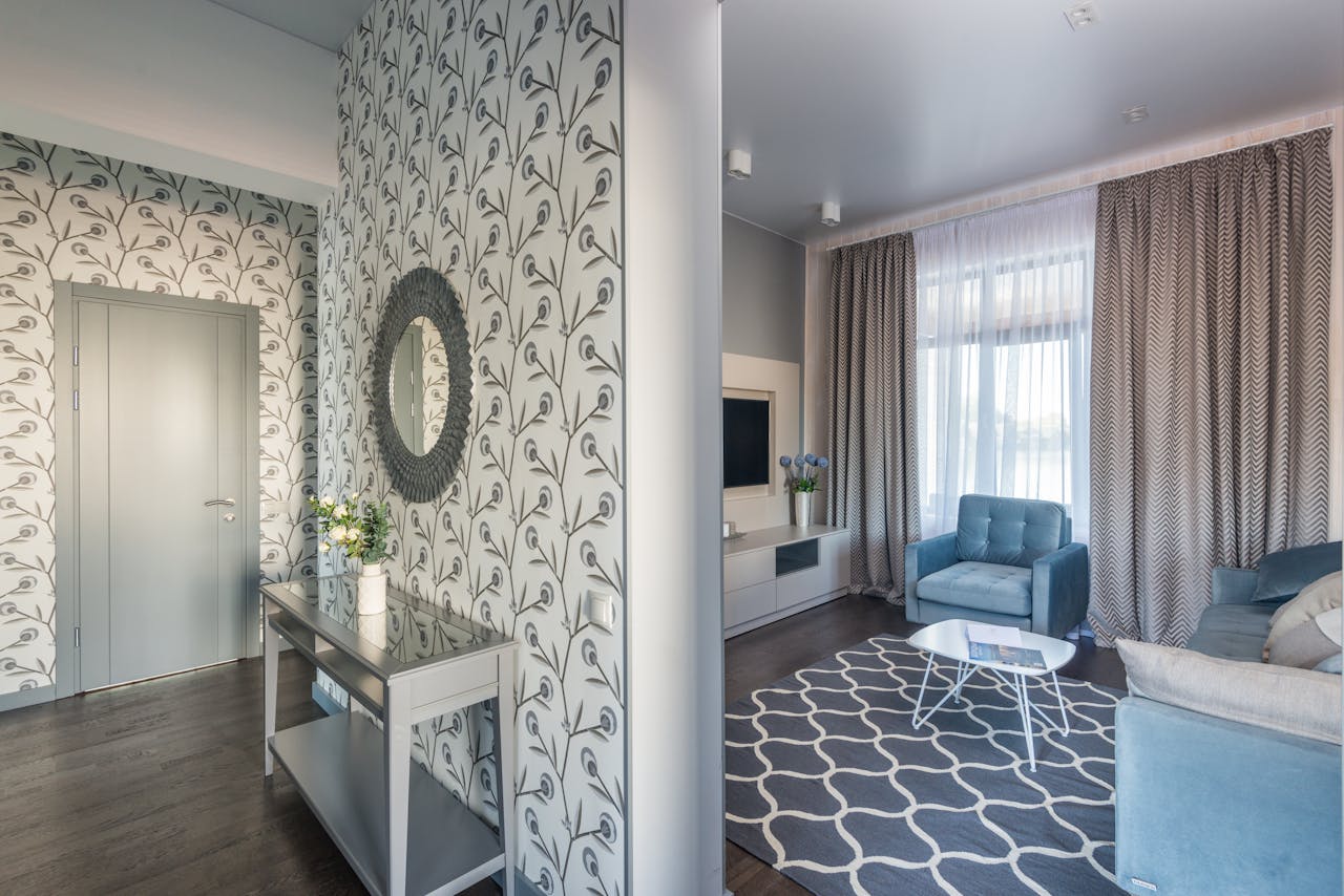 Entryway design with patterned wallpaper beside a blue living room